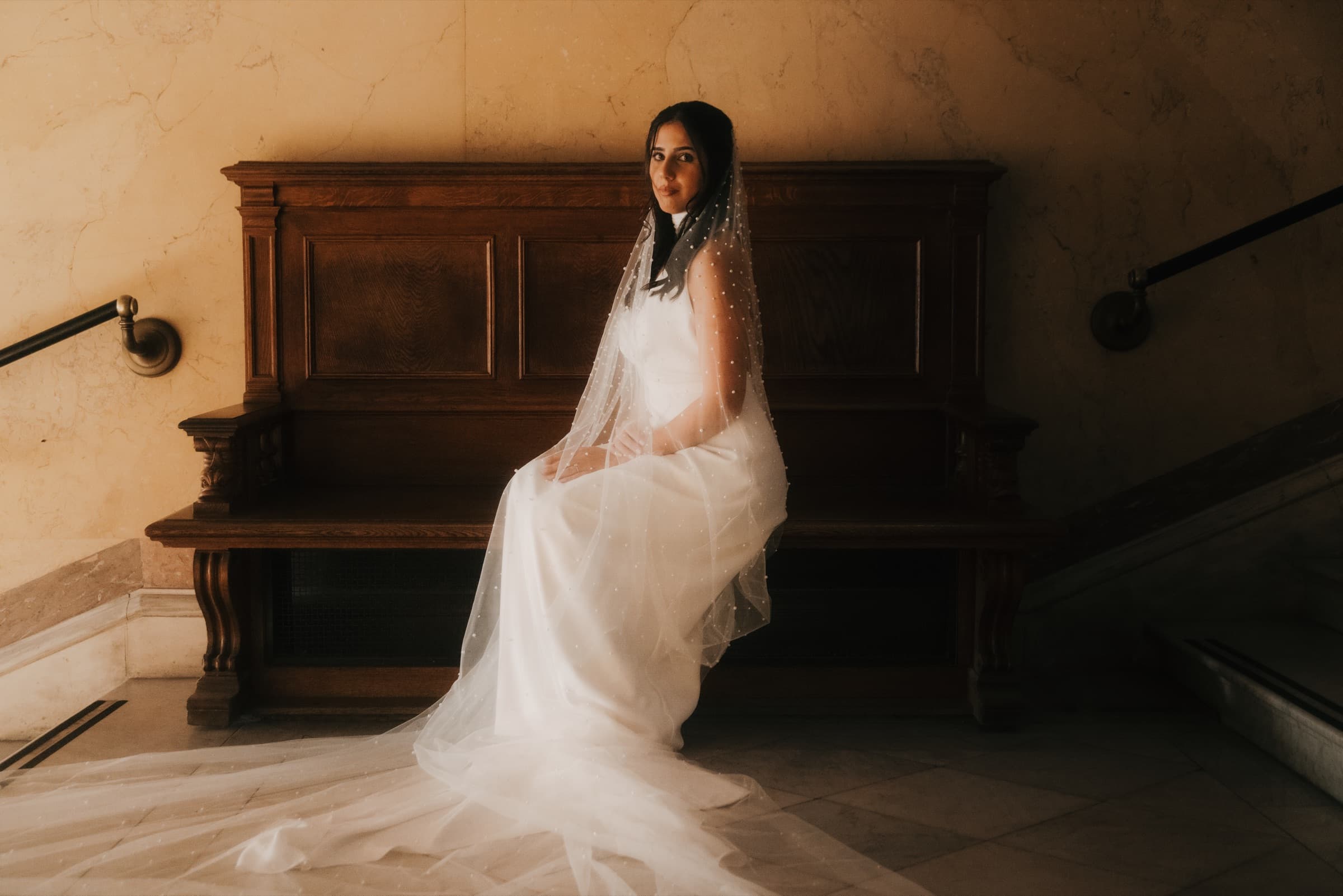 Bride seated at a piano with her veil draped