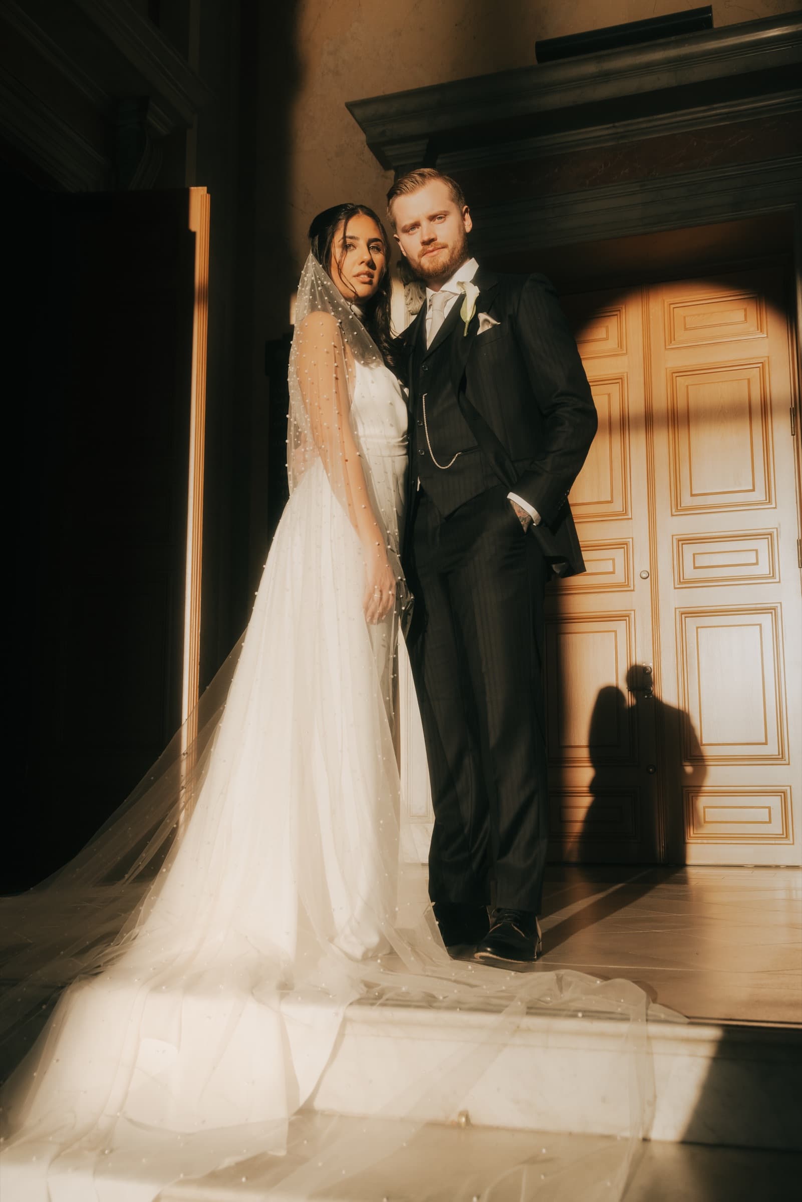 Couple in dramatic side light before a tall doorway