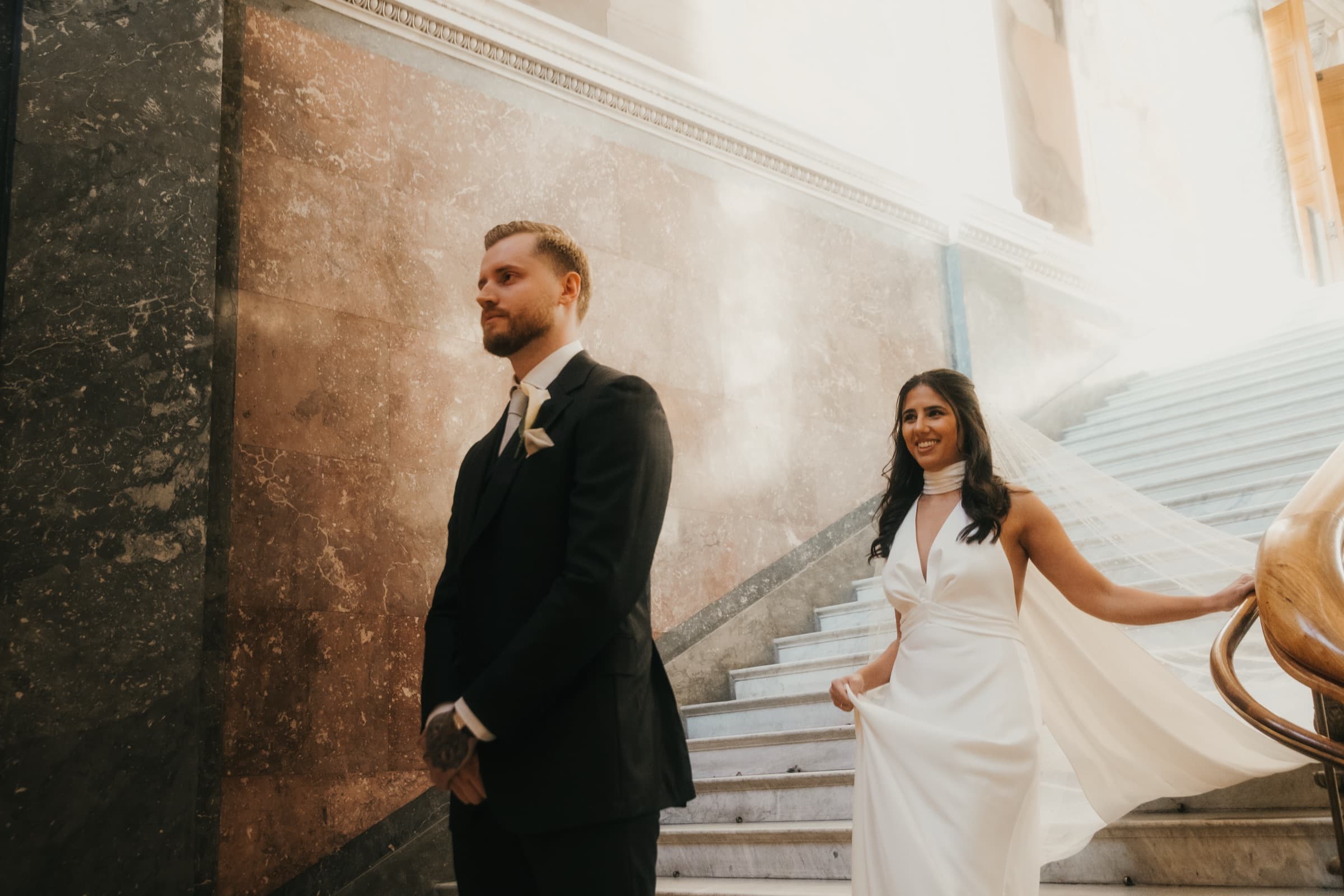 Bride in motion with her veil flowing, the groom beside her