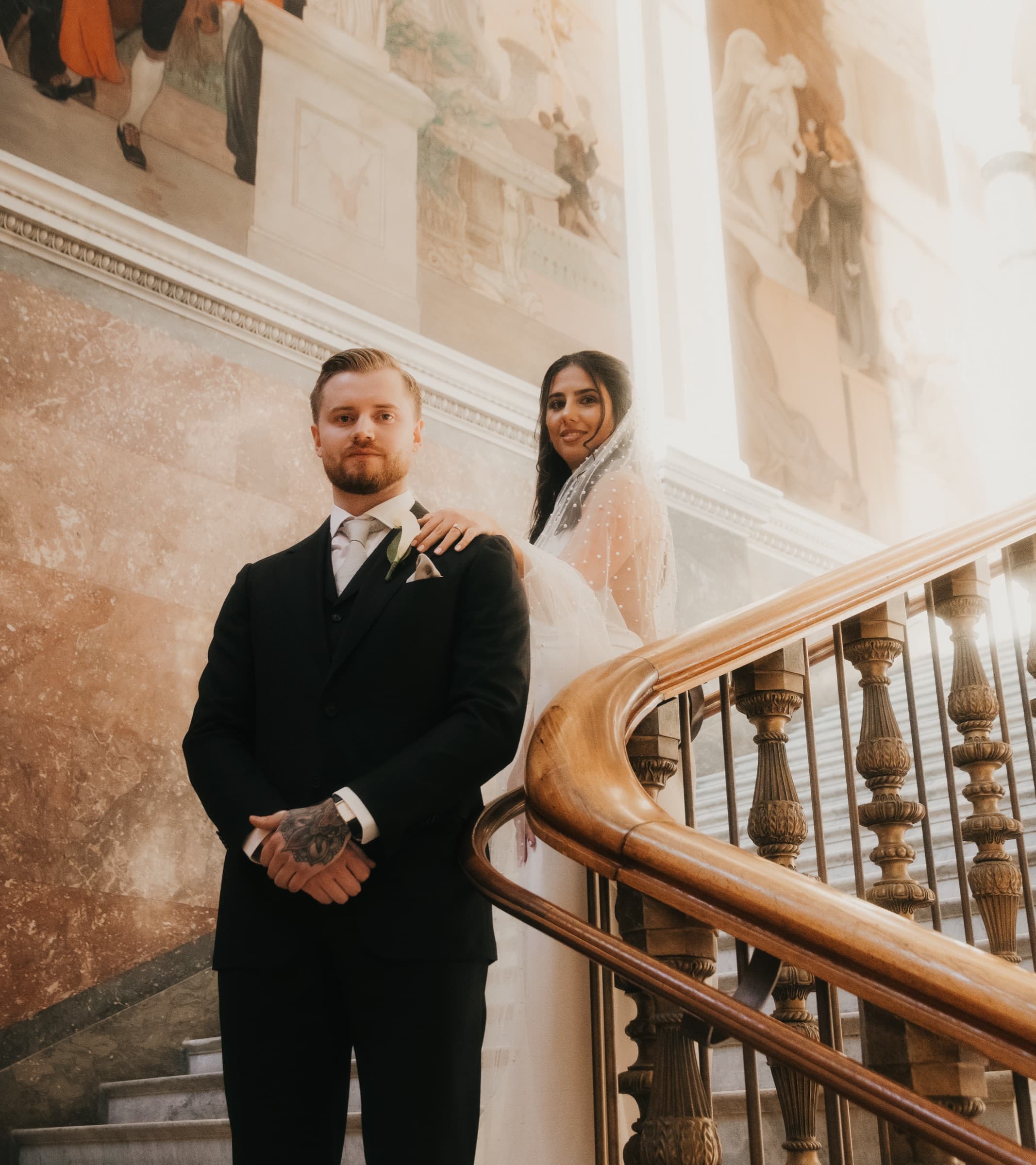 Couple on the grand staircase at Nationalmuseum, groom at the curved banister
