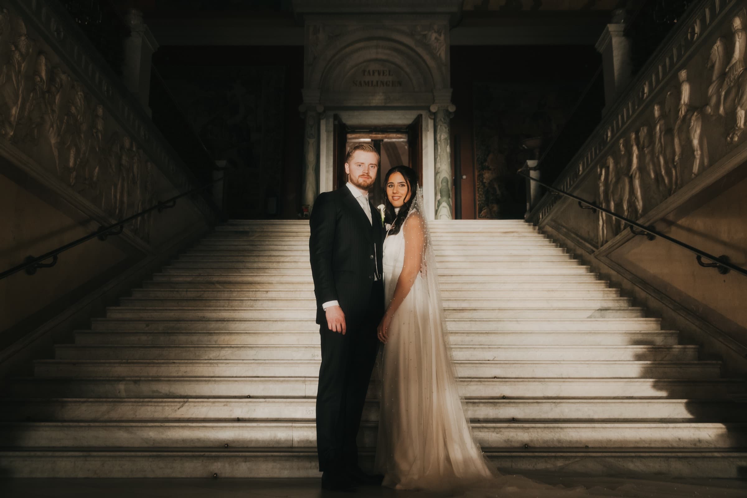 Couple centered on the symmetrical marble staircase