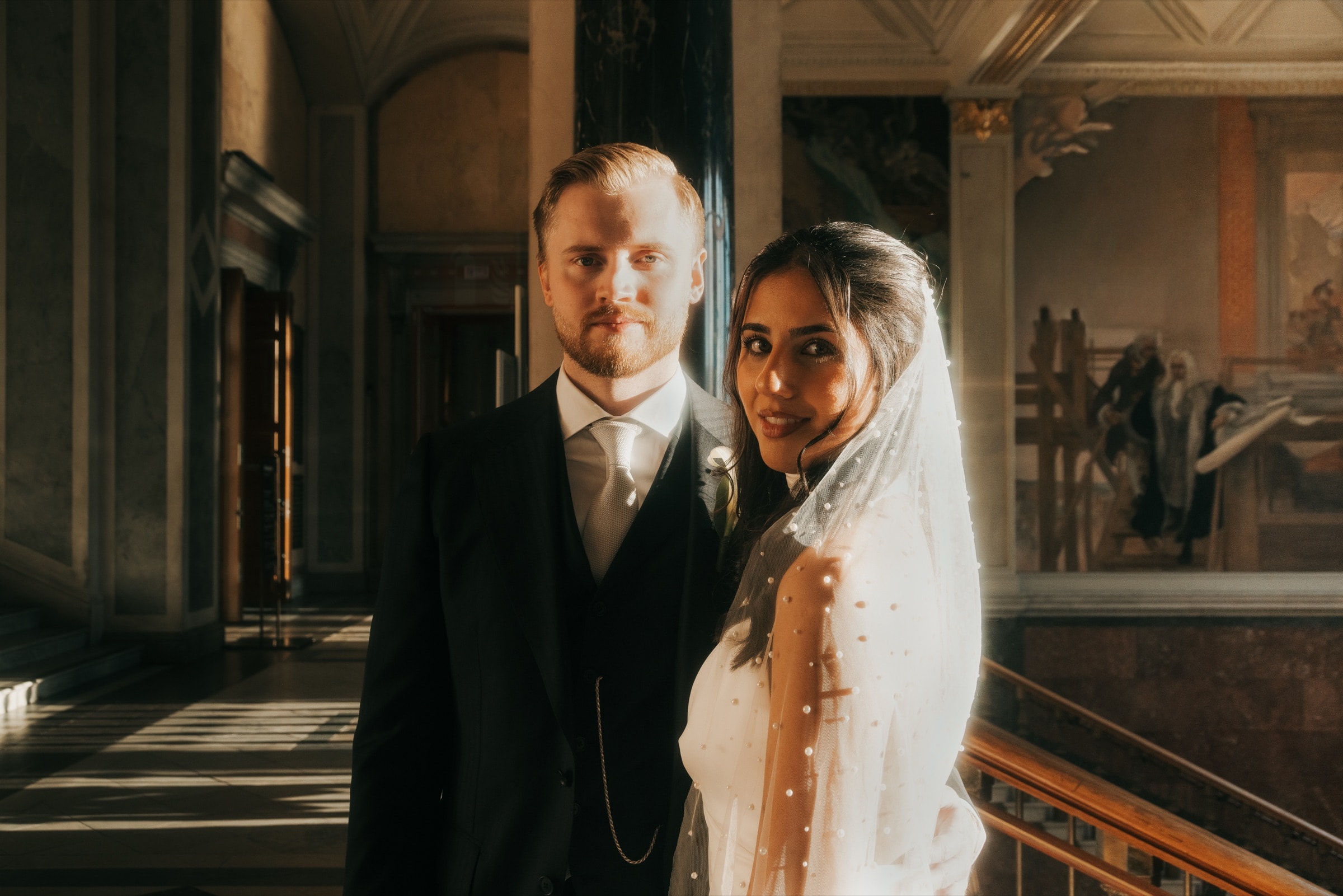 Couple in a colonnade with frescoes in warm light