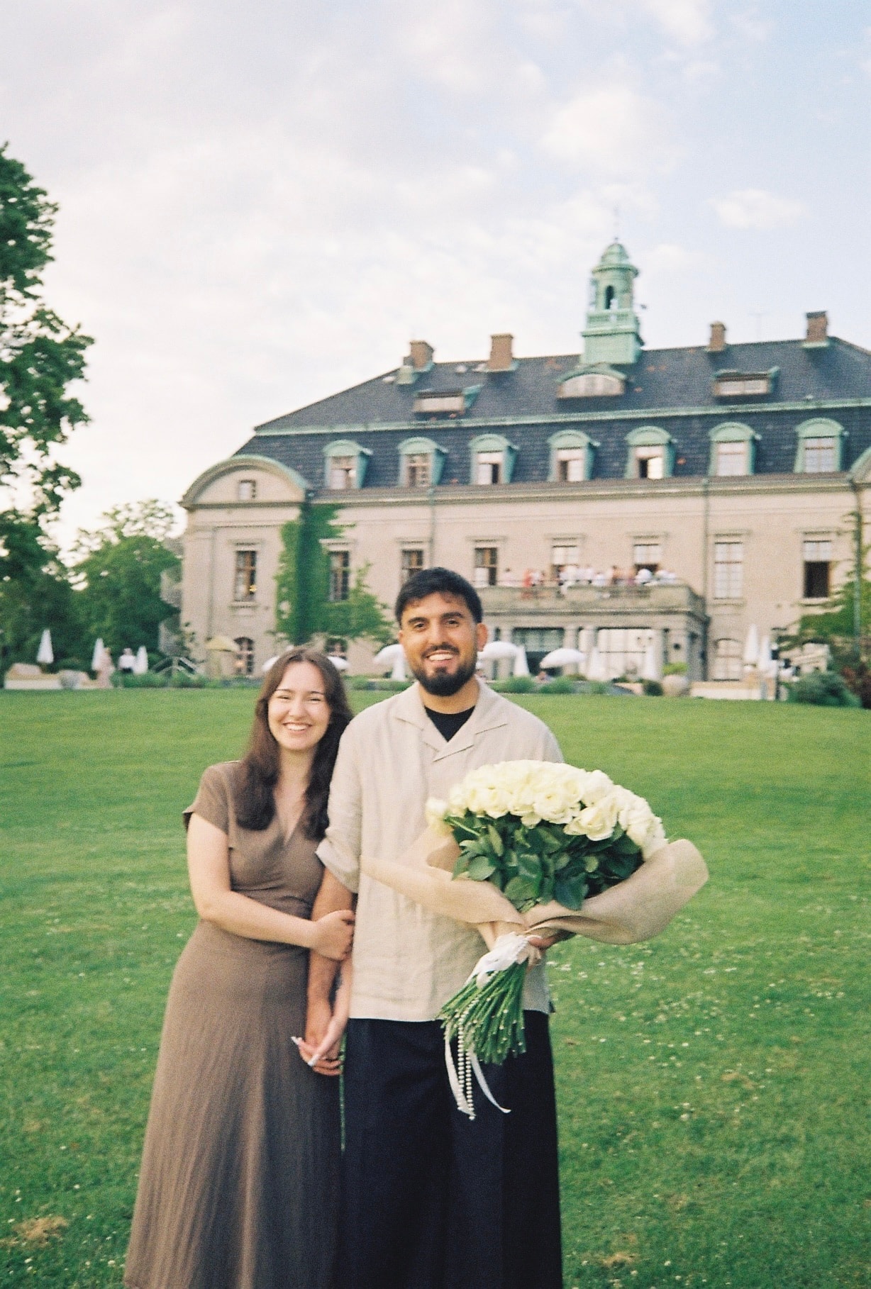 Zana och Anela, paret bakom Par Studio, framför en herrgård med en vit rosbukett